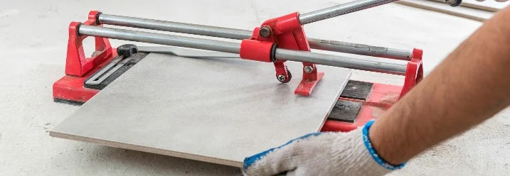 Person schneidet Fliese mit Fliesenschneider